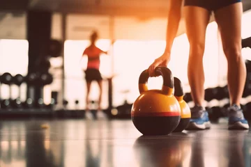Fotobehang Close up kettlebells with woman exercise workout in gym fitness breaking relax after sport training with protein shake bottle background. Healthy lifestyle bodybuilding and muscles, Generative AI © Focal Imaging