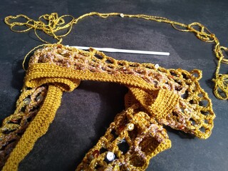 The process of crocheting from beads and sequins of golden color. Making a dress for a merry...