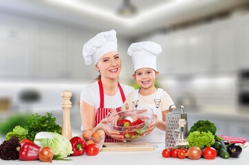 Attractive mother cooking with her cute daughter at home.