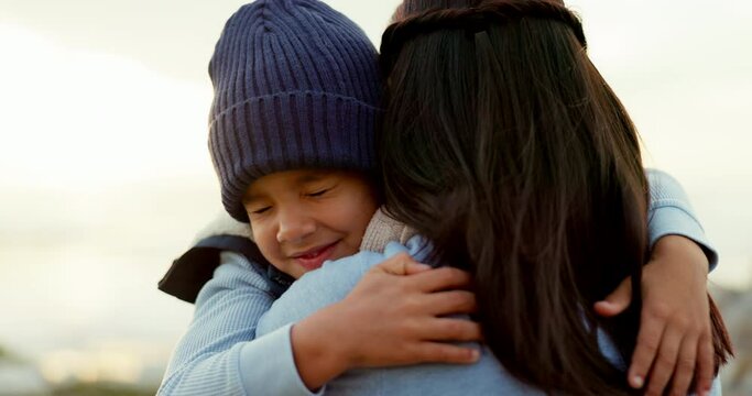 Security, mother and son hug outdoor, love and care at beach with travel and happiness in nature. Cold weather, winter and family, woman and young boy with smile, trust and safety with weekend trip