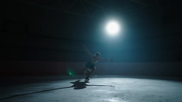 Silhouette Of Graceful Young Woman Figure Skater Spinning On Ice Rink, Portrait In Darkness