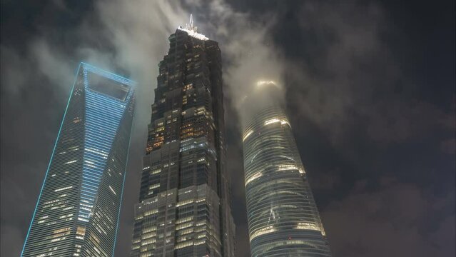 Night time lapse of clouds moving over the three most famous skyscrapers of Shanghai, skyline urban China
