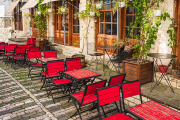 Fototapeta na wymiar Outdoor empty coffee and restaurant terrace with colorful tables and chairs. Old fashioned restaurant patio furniture