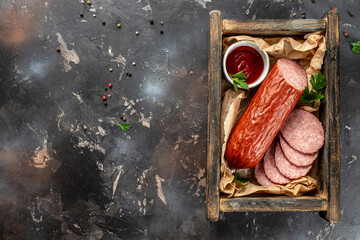 salami sausage in wooden box on a dark background. top view. copy space for text