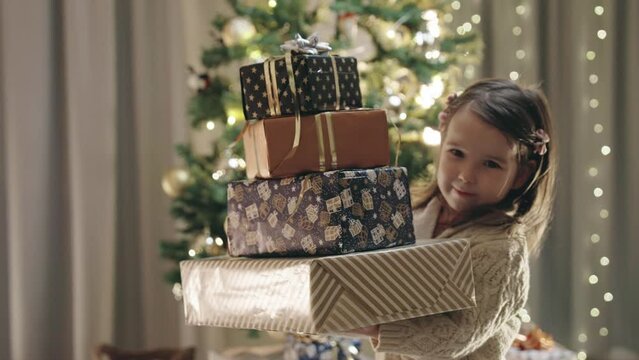 A Baby Girl Smiles and Holds Several Wrapped Christmas Gifts