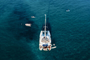 Drone view of Catamaran anchored in blue sea with swimming people in summer. Travel background....