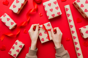Women hands pack gifts and make decorations for the holiday, top view. Birthday and valentine present