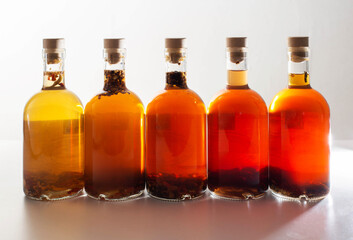Transparent bottles with brown alcoholic drink on a white background. The concept of homemade...