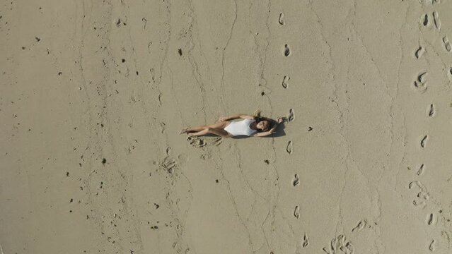 Aerial view of a woman relaxing on the beach along the shoreline in Ilot Lievres, Trou d'Eau Douce, Flacq districit, Mauritius.