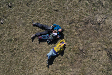 Obraz premium Aerial view of a happy family with, mom, dad and two kids laying in the grass