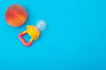 Peach with baby nibbler on a blue background. Concept of chewing reflex and feeding fruits and...