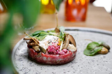 Beef tartare, tartar steak with pickles, on a plate, close up, selective focus. Dish of raw ground beef meat.