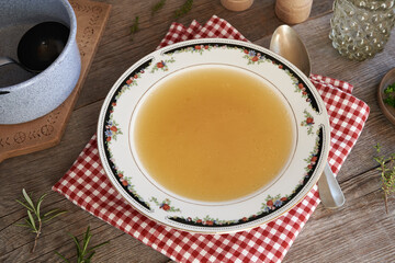 Chicken bone broth in a soup bowl on a table
