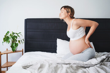 Pregnant woman suffering lower back pain, feeling unwell or sick.