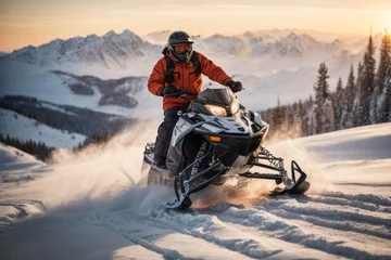 Poster A man wearing a insulated winter jacket and trousers rides a snowmobile leaving footprints in nature against the backdrop of high mountains with snow at sunset. Hobbies, outdoor activities © liliyabatyrova