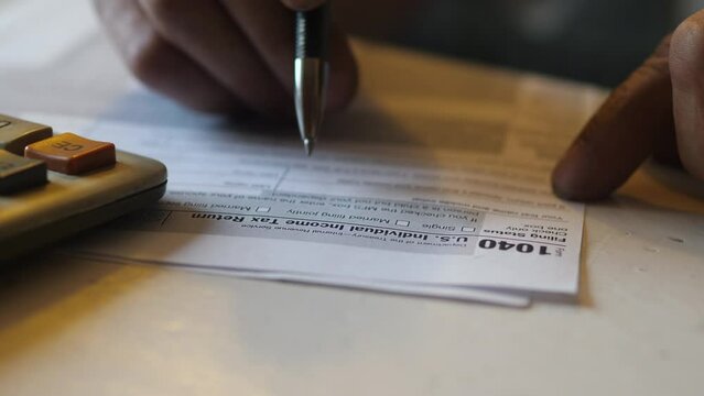 A pen and calculator sit on the 1040 U.S. personal income tax return. Time to pay taxes.
