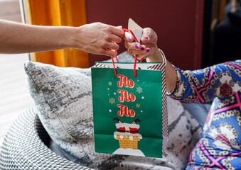 unrecognizable mature woman receiving a gift at christmastime. surprise in xmas with santa bag