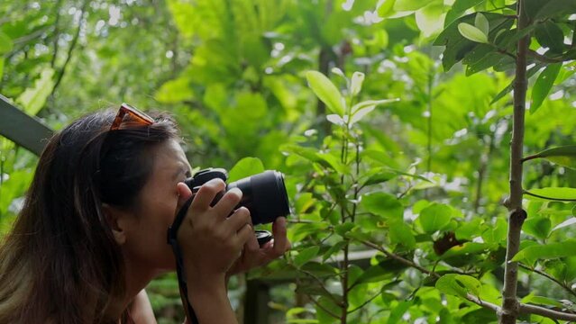 Young woman carefully capturing macro green plant photograph on camera