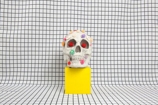  a skull covered with multiple plastic flowers on a white squared tile pattern