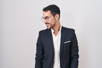Handsome business hispanic man standing over white background looking away to side with smile on face, natural expression. laughing confident.