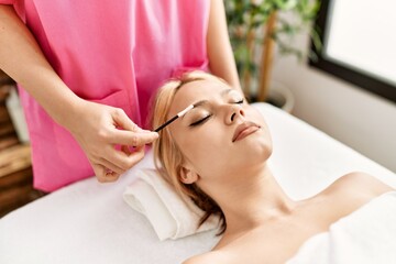 Fototapeta na wymiar Young caucasian woman lying on table having eyelashes treatment at beauty salon