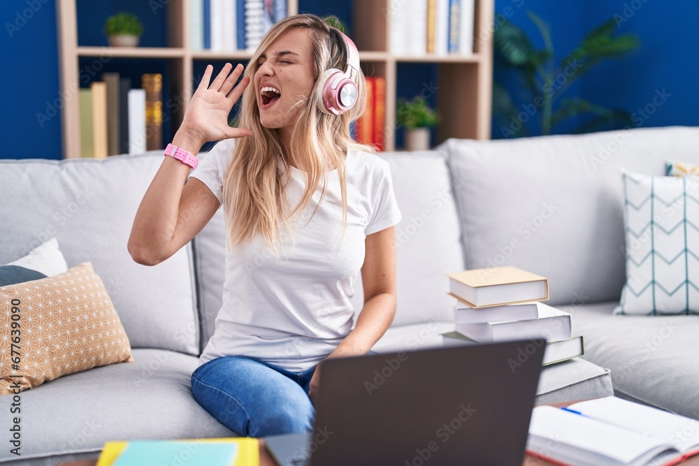 Sticker Young blonde woman studying using computer laptop at home shouting and screaming loud to side with hand on mouth. communication concept.