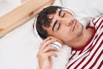 Fototapeta na wymiar Young hispanic man listening to music relaxed on bed at bedroom