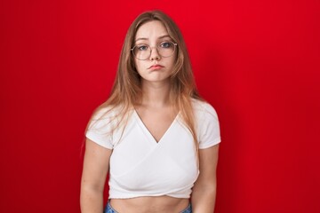 Young caucasian woman standing over red background depressed and worry for distress, crying angry...
