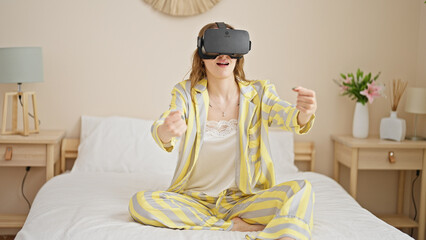 Young blonde woman playing video game using virtual glasses at bedroom