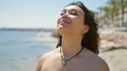 Young beautiful hispanic woman tourist wearing bikini breathing at beach