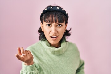 Young beautiful woman standing over pink background pointing displeased and frustrated to the camera, angry and furious with you