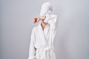 Blonde caucasian woman wearing bathrobe covering eyes with arm, looking serious and sad. sightless, hiding and rejection concept