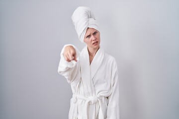 Blonde caucasian woman wearing bathrobe pointing displeased and frustrated to the camera, angry and furious with you