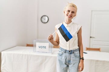 Young blonde woman holding estonia flag smiling at electoral college