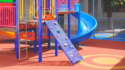 Colorful jungle gym and slide with outdoors playground equipment on rubber floor in kindergarten school 