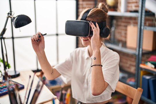 Young blonde woman smiling confident using virtual reality glasses drawing at art studio