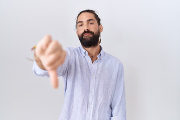 Fototapeta premium Hispanic man with beard wearing casual shirt looking unhappy and angry showing rejection and negative with thumbs down gesture. bad expression.