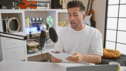 Attractive young hispanic man is a pro in the broadcast biz! in studio, podcast reporter reading...