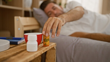 Worried young hispanic man lying in bed holding ill treatment pills, stressed about sickness in his...