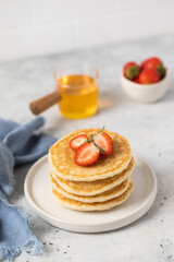 stack of pancakes with strawberries and honey