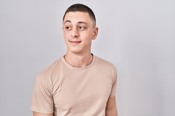 Young man standing over isolated background smiling looking to the side and staring away thinking.