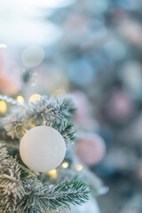 Christmas decorations. Hanging white ball on pine branches in the snow, and Christmas tree garland decorations on an abstract bokeh background with copy space