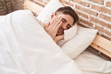 Young caucasian man stressed lying on bed at bedroom