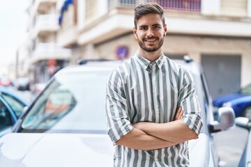 Young caucasian man smiling confident standing by car with arms crossed gesture at street