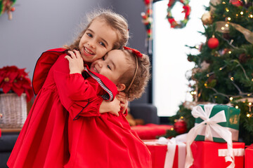 Adorable girls hugging each other celebrating christmas at home