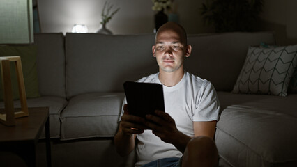 Young hispanic man using touchpad sitting on floor at home