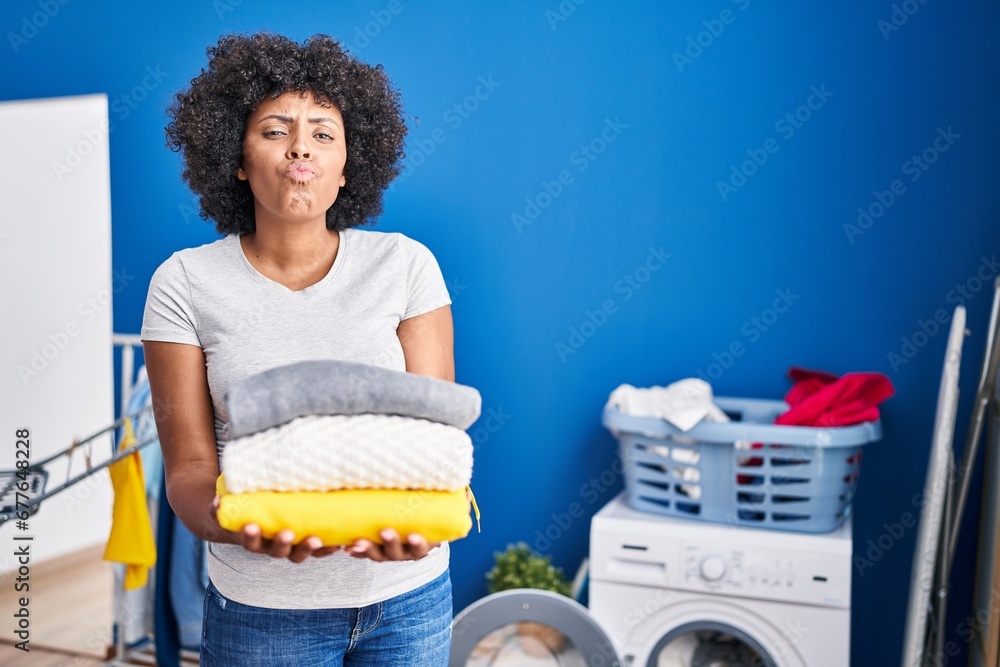 Canvas Prints black woman with curly hair holding clean laundry looking at the camera blowing a kiss being lovely 