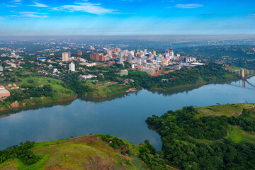 Aerial view of the Paraguayan city of Ciudad del Este and Friendship Bridge, connecting Paraguay and Brazil through the border over the Parana River,. - obrazy, fototapety, plakaty