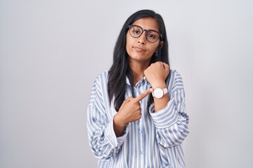 Young hispanic woman wearing glasses in hurry pointing to watch time, impatience, looking at the...
