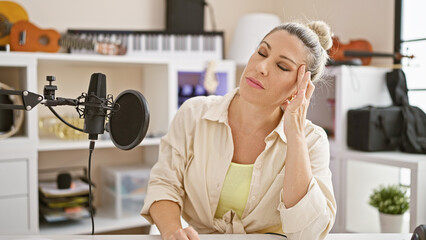 Young blonde woman reporter working on radio show stressed at radio studio